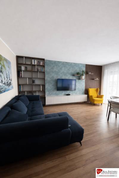 Predaj 3-izbový byt s terasou 20m2, parkovanie, Dunajská Lužná - Obývačka s modrou sedačkou, žltým kreslom a podlahou s dreveným dekorom v 3-izbovom byte.