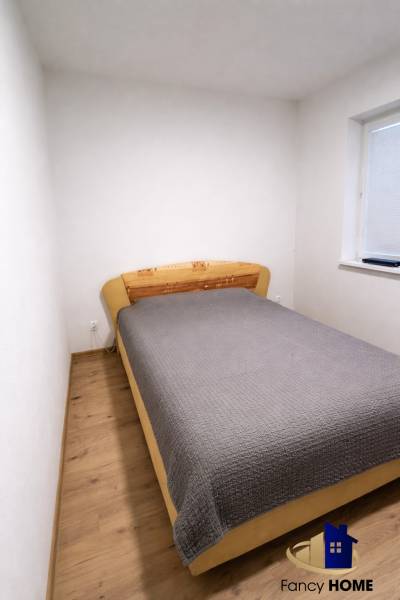 Moderný 2-izbový byt v centre Kežmarku na predaj - Spálňa s posteľou a podlahou s dreveným dekorom v 2-izbovom byte.