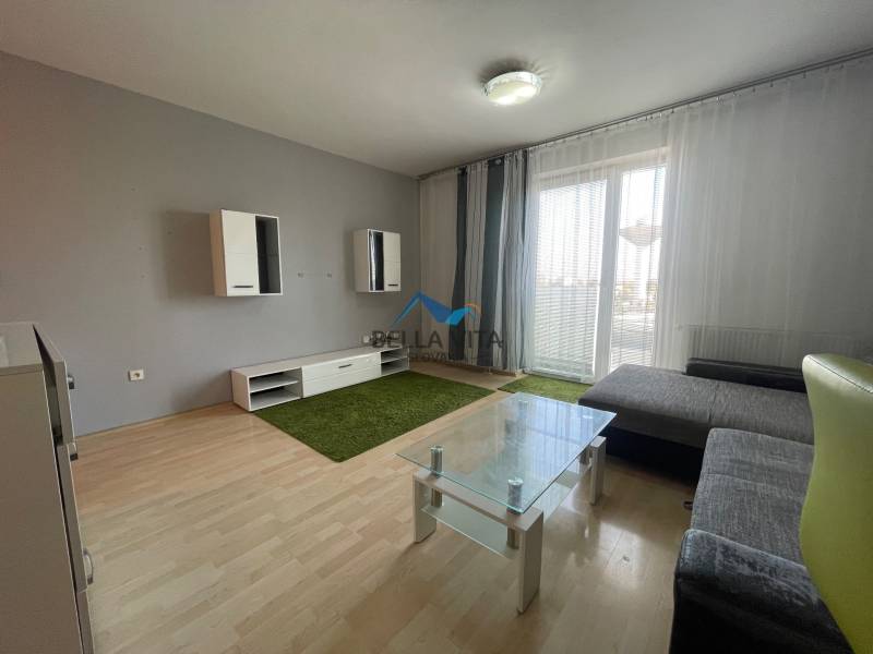 Prenájom 1 izbový byt v Galante, Hodská - Obývacia izba v 1-izbovom byte s podlahou s dreveným dekorom, pohovkou a sklom stolíkom.