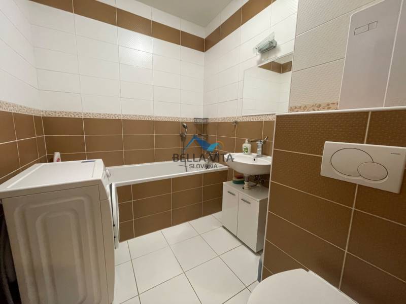 Prenájom 1 izbový byt v Galante, Hodská - Kúpeľňa v 1-izbovom byte s práčkou, vaňou a umývadlom, obklad v hnedo-bielej kombinácii.