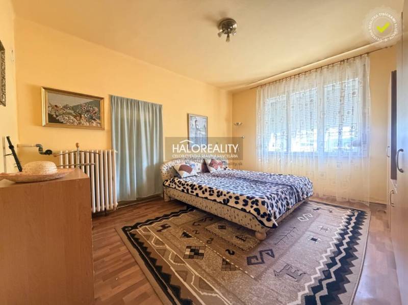 Predaj, rodinný dom Dvory nad Žitavou, päťizbový  - Spálňa v rodinnom dome s podlahou s dreveným dekorom, veľkým oknom a kobercami.