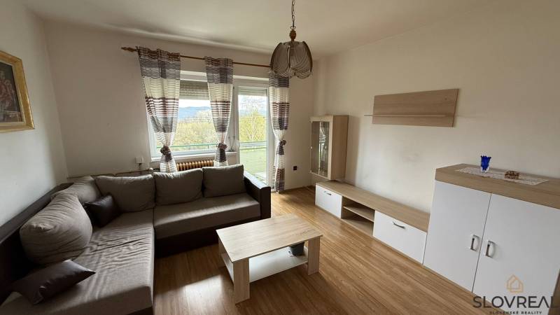 Na predaj 3i byt Pukanec - Obývačka v 3-izbovom byte s pohodlnou sedačkou, podlahou s dreveným dekorom a balkónom.