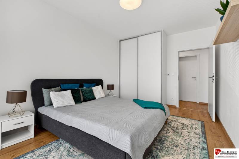 Predaj 2-izbový byt GREEN VILLAGE, 51m2, loggia, Dunajská Lužná - Spálňa v 2-izbovom byte s posteľou, nočným stolíkom a skriňou.