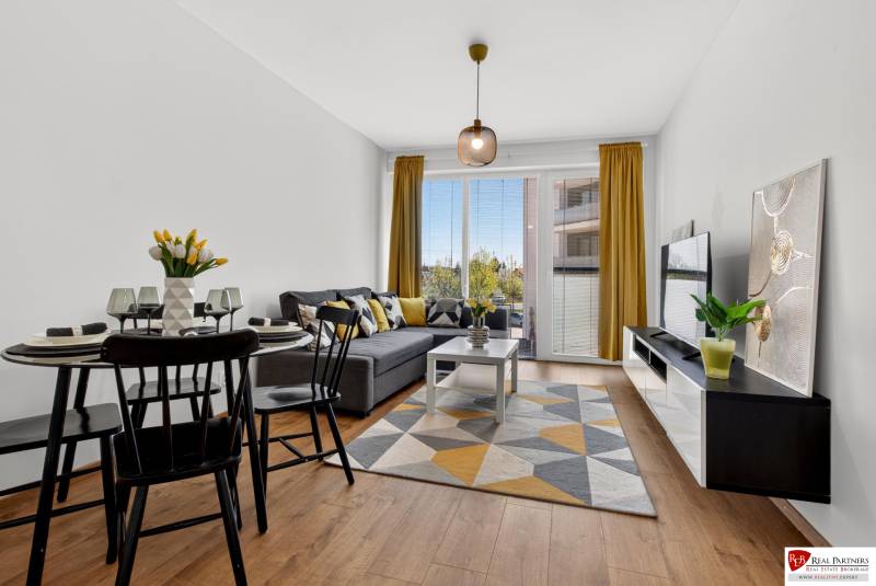 Predaj 2-izbový byt GREEN VILLAGE, 51m2, loggia, Dunajská Lužná - Obývačka v 2-izbovom byte s podlahou s dreveným dekorom, pohovkou a jedálenským stolom.