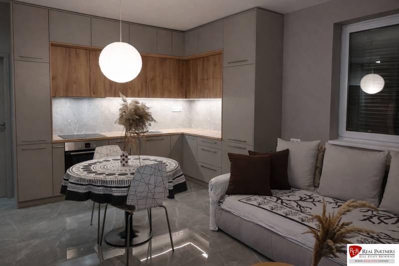 Predaj 2-izbový byt GREEN VILLAGE,44m2, loggia, Dunajská Lužná - Kuchyňa v 2-izbovom byte s podlahou s dreveným dekorom a okrúhlym stolom.