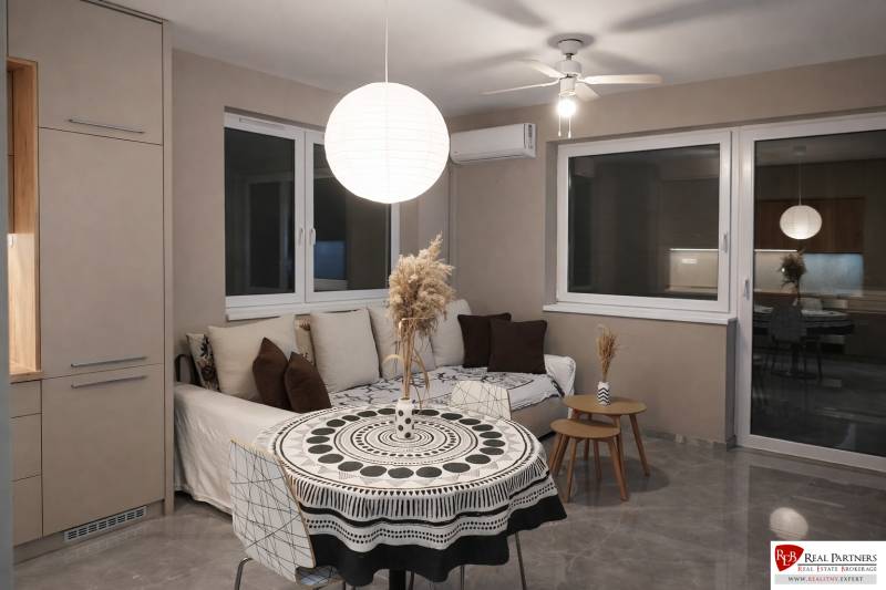 Predaj 2-izbový byt GREEN VILLAGE,44m2, loggia, Dunajská Lužná - Obývacia izba s pohovkou, okrúhlym stolom a ozdobným svietidlom v 2-izbovom byte.