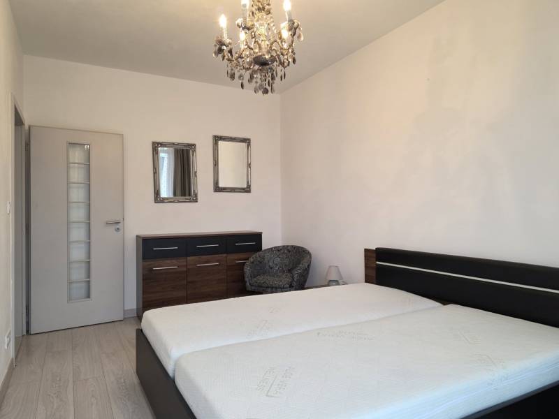 PRENÁJOM - 3 izbový byt v novostavbe - Nitra, blízko centra - Spálňa so svetlou podlahou s dreveným dekorom, pohodlnou posteľou a lustrom v 3-izbovom byte.