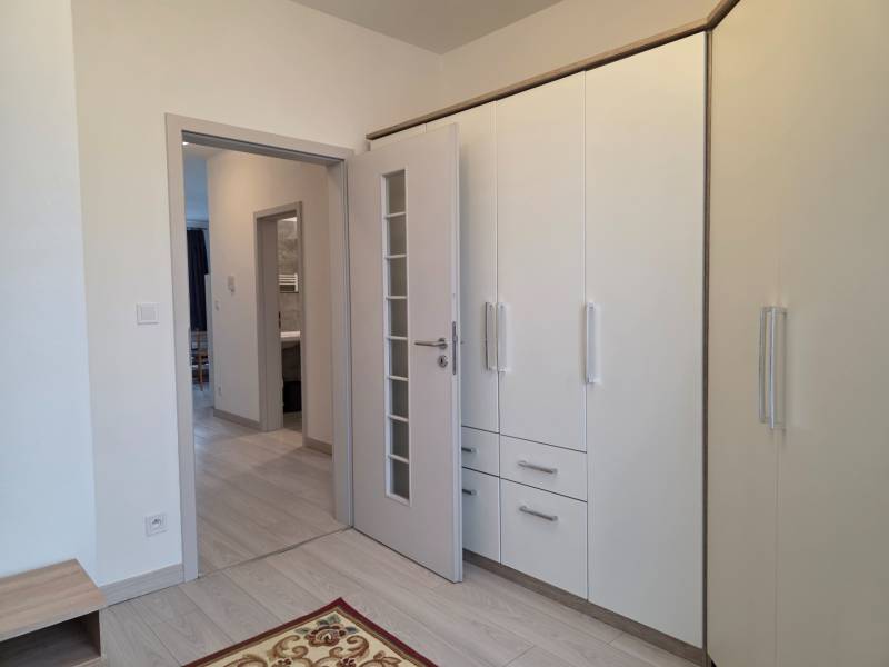 PRENÁJOM - 3 izbový byt v novostavbe - Nitra, blízko centra - Interiér 3-izbového bytu s bielou vstavanou skriňou a podlahou s dreveným dekorom.