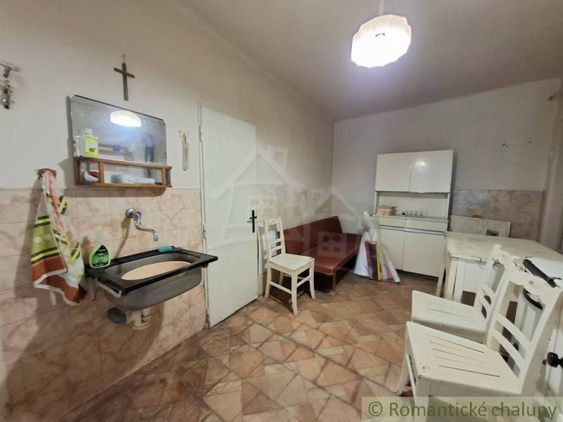 Pôvodný päťizbový rodinný dom s hospodárskymi budovami blízko centra o - Interiér rodinného domu s kachličkovanou stenou, nábytkom a drezom.