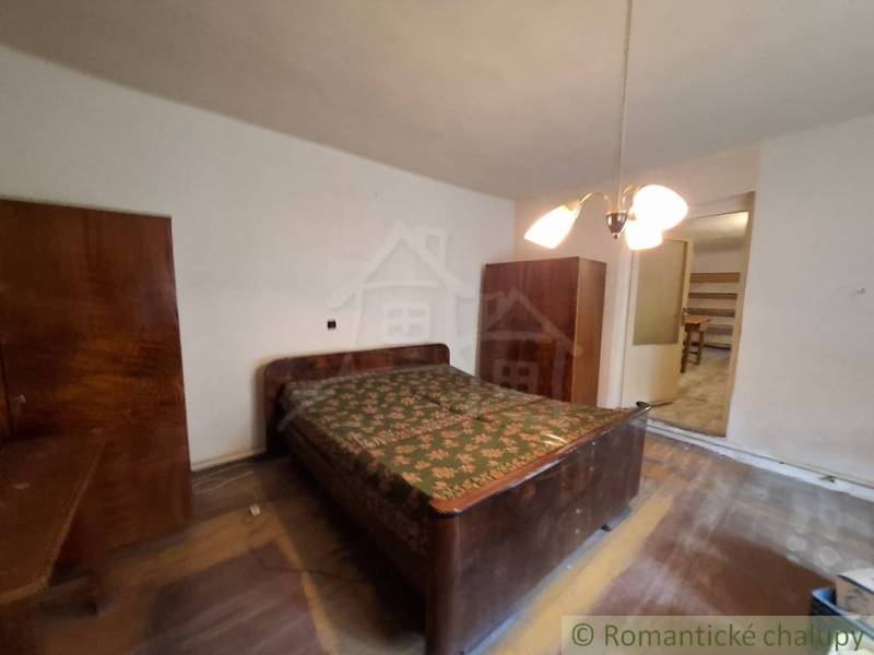 Pôvodný päťizbový rodinný dom s hospodárskymi budovami blízko centra o - Spálňa v rodinnom dome s drevenými skrinkami a podlahou s dreveným dekorom.