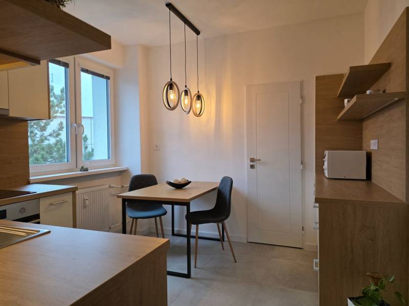 PRENÁJOM - Priestranný 3 izbový byt - Nitra, Centrum - Kuchyňa v 3-izbovom byte s podlahou s dreveným dekorom a závesnými svietidlami.