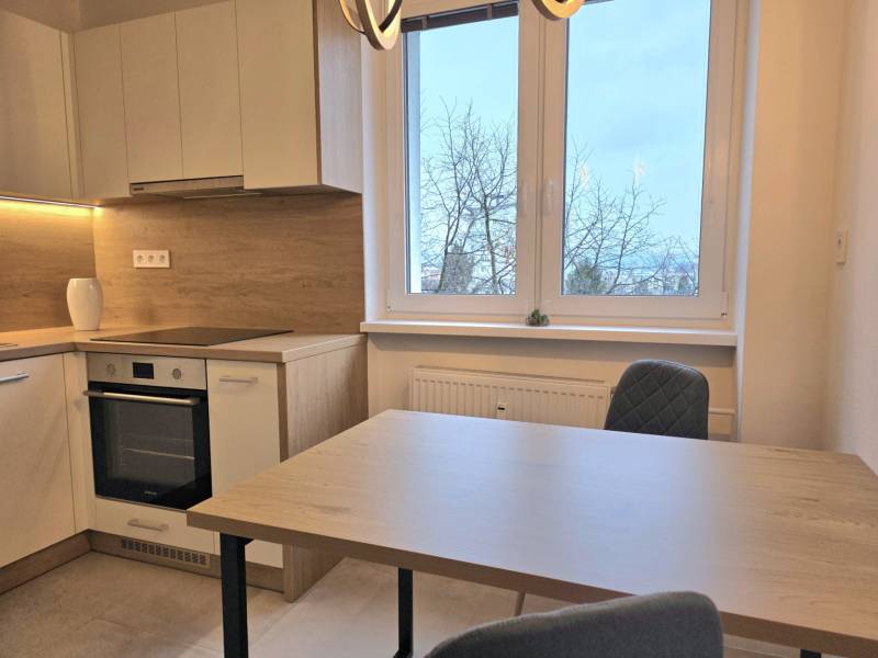 PRENÁJOM - Priestranný 3 izbový byt - Nitra, Centrum - Kuchyňa s kuchynskou linkou, jedálenským stolom a stoličkami, v 3-izbovom byte s podlahou s dreveným dekorom.