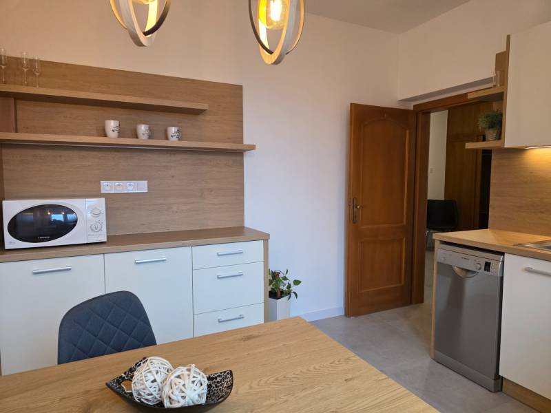 PRENÁJOM - Priestranný 3 izbový byt - Nitra, Centrum - Kuchyňa so stolom a stoličkou v 3-izbovom byte, s dreveným dekorom a mikrovlnkou.