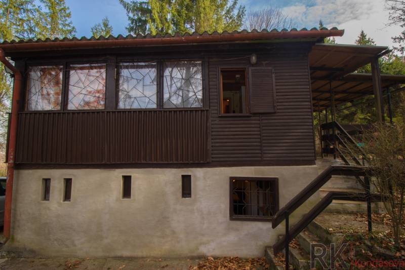 Chata na Domaši, Holčíkovce, Poľany-Monika - Drevená chata na rekreačných pozemkoch v Holčíkovciach obklopená zeleňou a stromami.