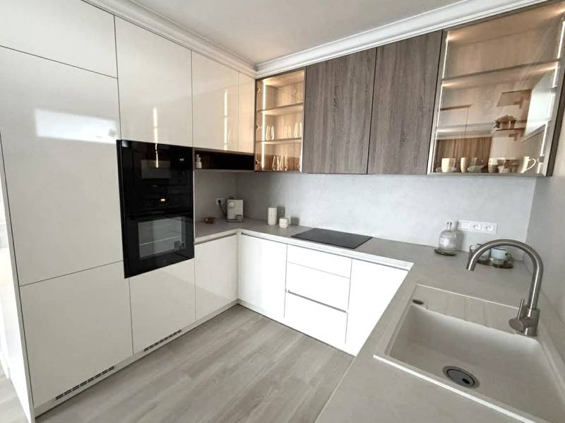 2 izbový A.3.1.- 58,91 m2 Bell Residence  - Kuchyňa v 2-izbovom byte s bielymi skrinkami a podlahou s dreveným dekorom.