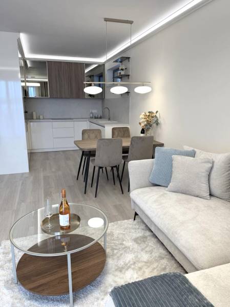 2 izbový A.3.1.- 58,91 m2 Bell Residence  - Obývacia izba v 2-izbovom byte s podlahou s dreveným dekorom, pohovkou a jedálenským stolom.