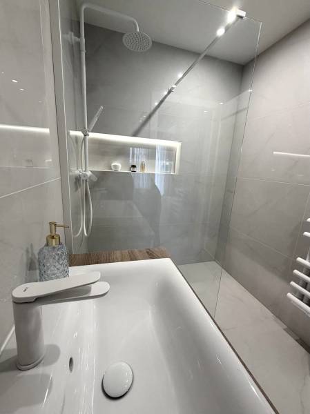2 izbový A.3.1.- 58,91 m2 Bell Residence  - Kúpeľňa so sprchovým kútom a umývadlom v 2-izbovom byte s podlahou s dreveným dekorom.