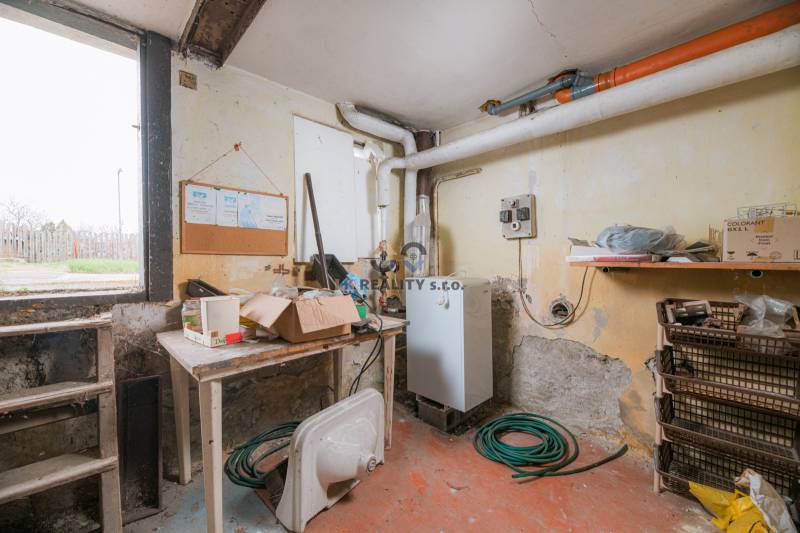 Na predaj rodinný dom Trnava, Zelenečská ulica, pozemok 1085 m2 - Suterén Rodinného domu s kotlom, regálmi, hadicou a stolom na prácu.