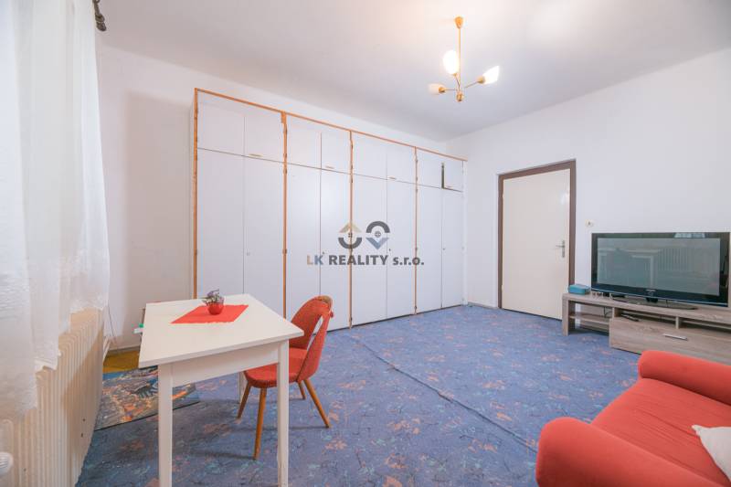 Na predaj rodinný dom Trnava, Zelenečská ulica, pozemok 1085 m2 - Obývacia izba v rodinnom dome s modrým kobercom, rozkladacím gaučom a úložnými skriňami.