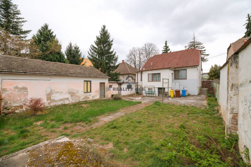 Na predaj rodinný dom Trnava, Zelenečská ulica, pozemok 1085 m2 - Záhrada a budovy rodinného domu na Zelenečskej ulici v Trnave obkolesené stromami.