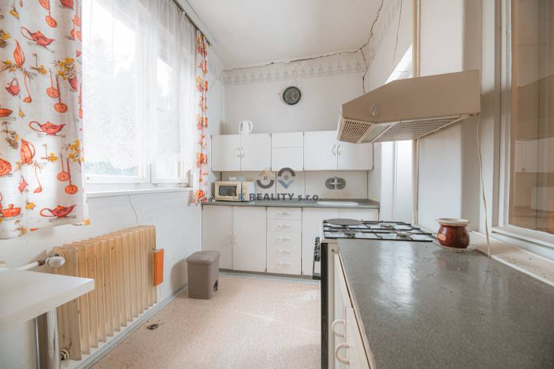 Na predaj rodinný dom Trnava, Zelenečská ulica, pozemok 1085 m2 - Kuchyňa v rodinnom dome s bielymi skrinkami, sporákom a farebnými záclonami.