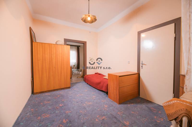 Na predaj rodinný dom Trnava, Zelenečská ulica, pozemok 1085 m2 - Izba v rodinnom dome s modrým kobercom, dreveným nábytkom a posteľou.