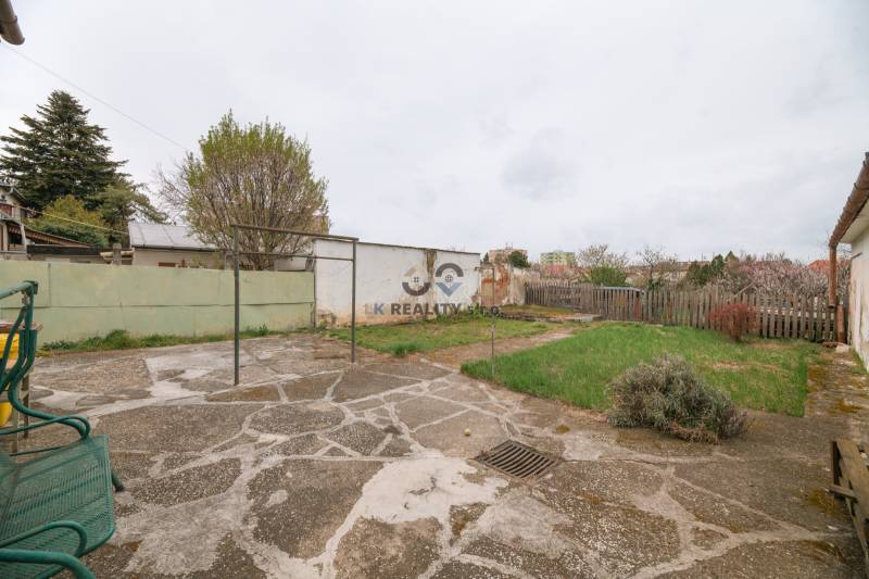 Na predaj rodinný dom Trnava, Zelenečská ulica, pozemok 1085 m2 - Záhrada pri rodinnom dome na Zelenečskej ulici v Trnave s trávnikom a dlažbou.