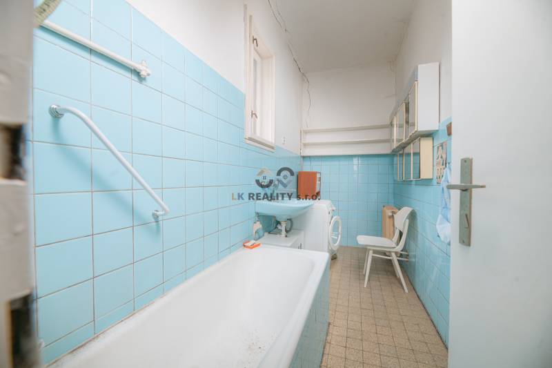 Na predaj rodinný dom Trnava, Zelenečská ulica, pozemok 1085 m2 - Kúpeľňa s modrými obkladačkami, umývadlom, vaňou, práčkou a policami v Rodinnom dome.