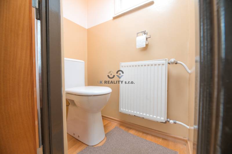 Na predaj rodinný dom Trnava, Zelenečská ulica, pozemok 1085 m2 - Toaleta v rodinnom dome s radiátorom a podlahou s dreveným dekorom.