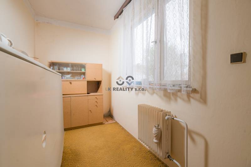 Na predaj rodinný dom Trnava, Zelenečská ulica, pozemok 1085 m2 - Izba v Rodinnom dome so starším nábytkom, radiátorom a kobercom.