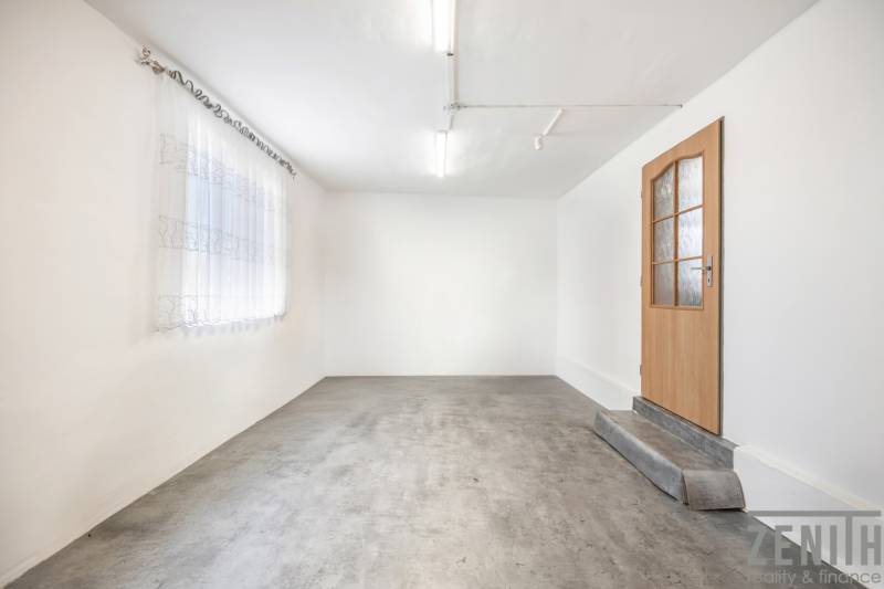 Komerčný objekt s pozemkom – možnosť zmeny na rodinný dom - Biele steny, betónová podlaha, drevené dvere a záclona v obchodných priestoroch.