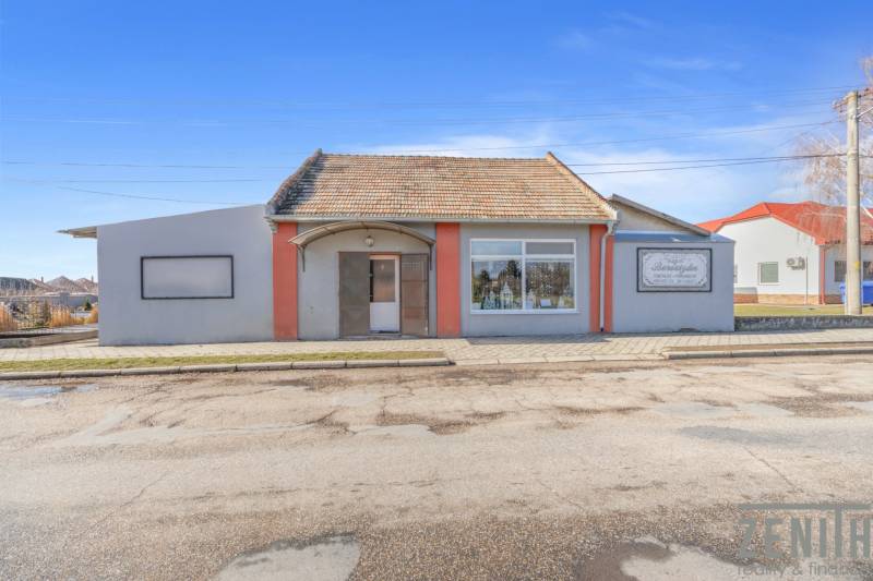 Komerčný objekt s pozemkom – možnosť zmeny na rodinný dom - Obchodné priestory v meste Okoč s výkladnými oknami a šikmou strechou.