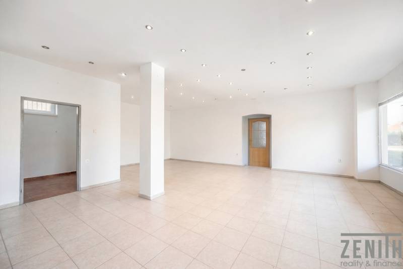 Komerčný objekt s pozemkom – možnosť zmeny na rodinný dom - Priestranné obchodné priestory s bielymi stenami, dlažbou a rozsvietenými stropnými svetlami.