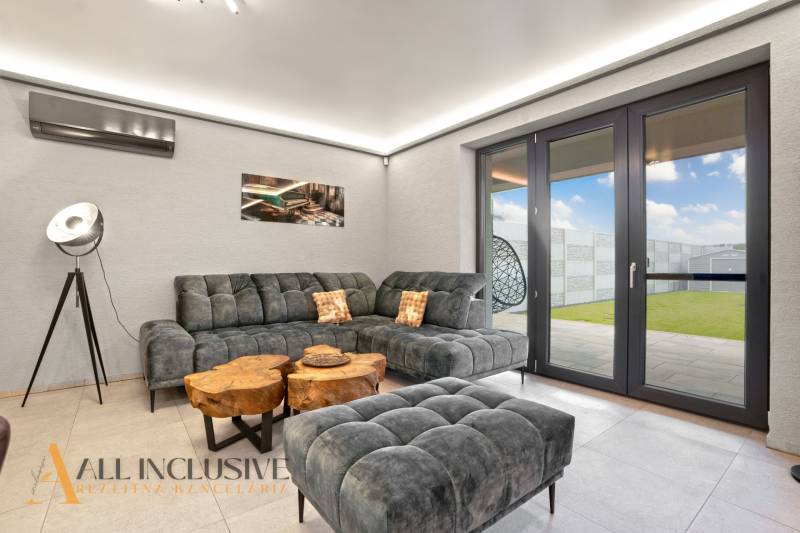 ALL INCLUSIVE I  4- IZBOVÝ RD SMART HOME NOVOSTAVBA- MOSTOVÁ (GA) - Obývacia izba v rodinnom dome s pohodlnou sedačkou, dreveným stolíkom a veľkými oknami.