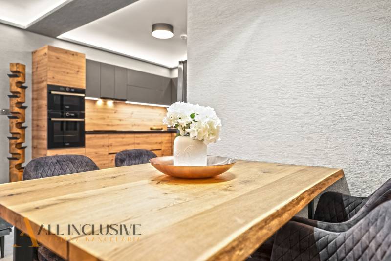 ALL INCLUSIVE I  4- IZBOVÝ RD SMART HOME NOVOSTAVBA- MOSTOVÁ (GA) - Kuchyňa v rodinnom dome s dreveným dekorom, bielou stenou a kvetinovou výzdobou.