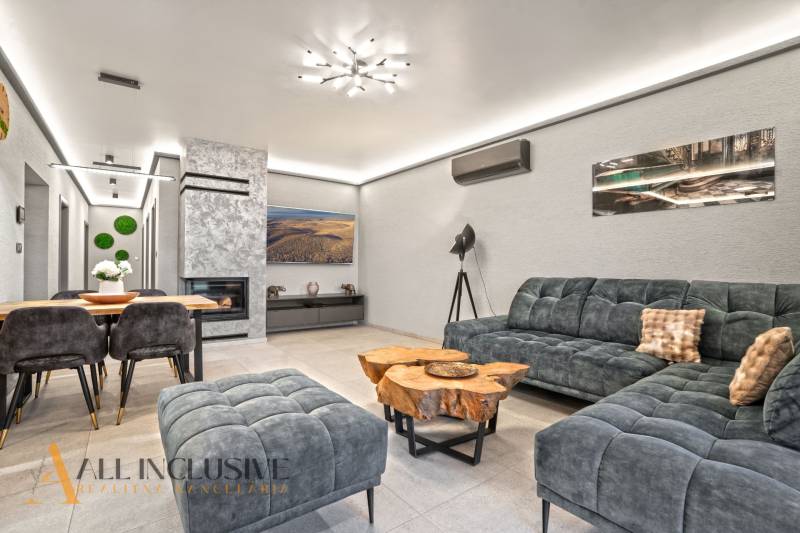 ALL INCLUSIVE I  4- IZBOVÝ RD SMART HOME NOVOSTAVBA- MOSTOVÁ (GA) - Interiér rodinného domu s pohodlnou sedačkou, krbom a stolom z dreveného dekoru.