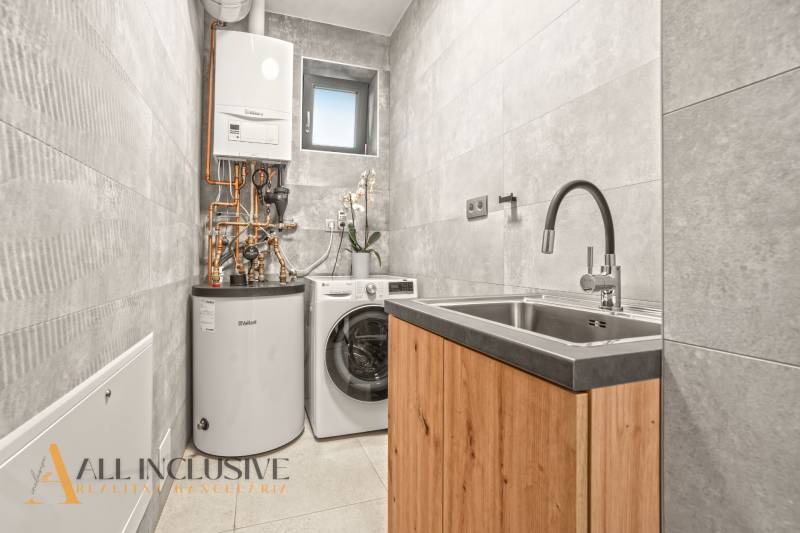 ALL INCLUSIVE I  4- IZBOVÝ RD SMART HOME NOVOSTAVBA- MOSTOVÁ (GA) - Práčovňa v rodinnom dome s práčkou, zásobníkom a umývadlom na podlahe s dreveným dekorom.