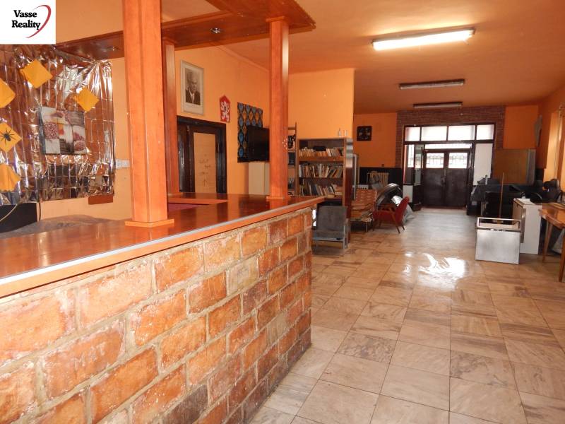  Podnikateľská príležitosť v obci Búč . - Interiér gastro priestoru so stolíkom a regálmi na knihy.