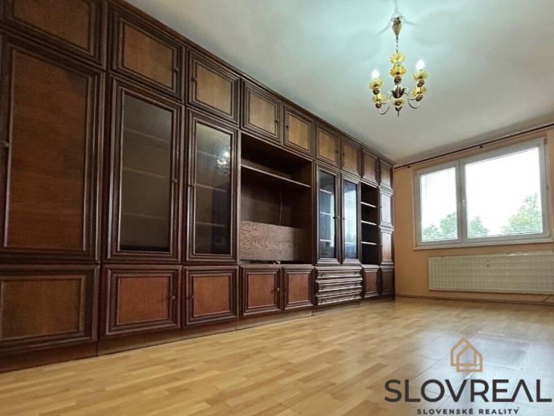 Na predaj 2i byt Levice - Obývacia izba s drevenou skriňou a podlahou s dreveným dekorom v 2-izbovom byte.