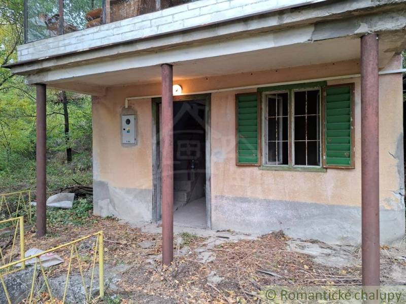 Pôvodná chata s panorámou nad korunami stromov blízko Hrona v rekreačn - Chata v Kameníne s verandou a zelenými okenicami obklopená prírodou.