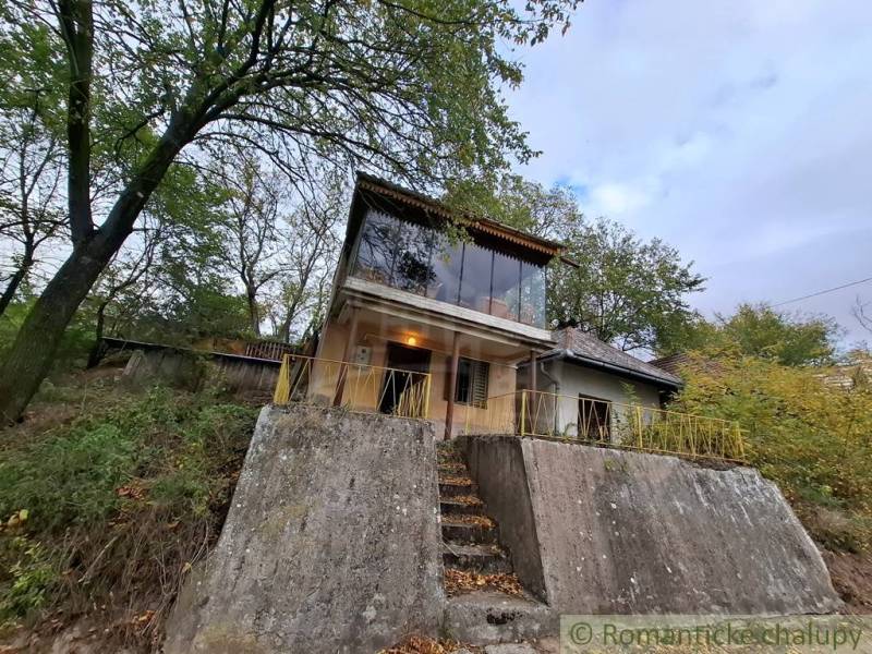 Pôvodná chata s panorámou nad korunami stromov blízko Hrona v rekreačn - Chata v Kameníne s betónovým základom a veľkými oknami uprostred stromov.
