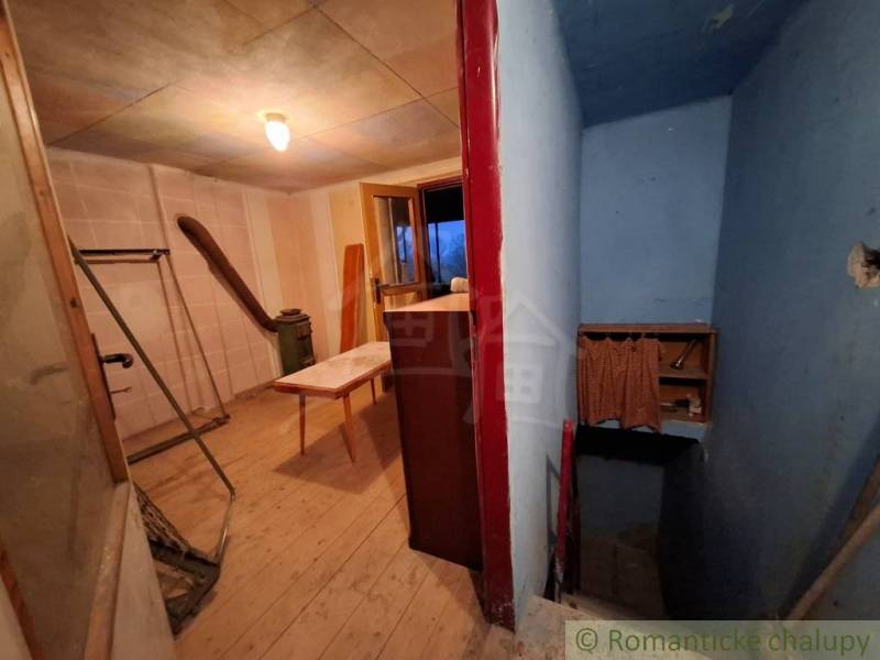 Pôvodná chata s panorámou nad korunami stromov blízko Hrona v rekreačn - Interiér chaty s podlahou s dreveným dekorom, chodbou a stolom.
