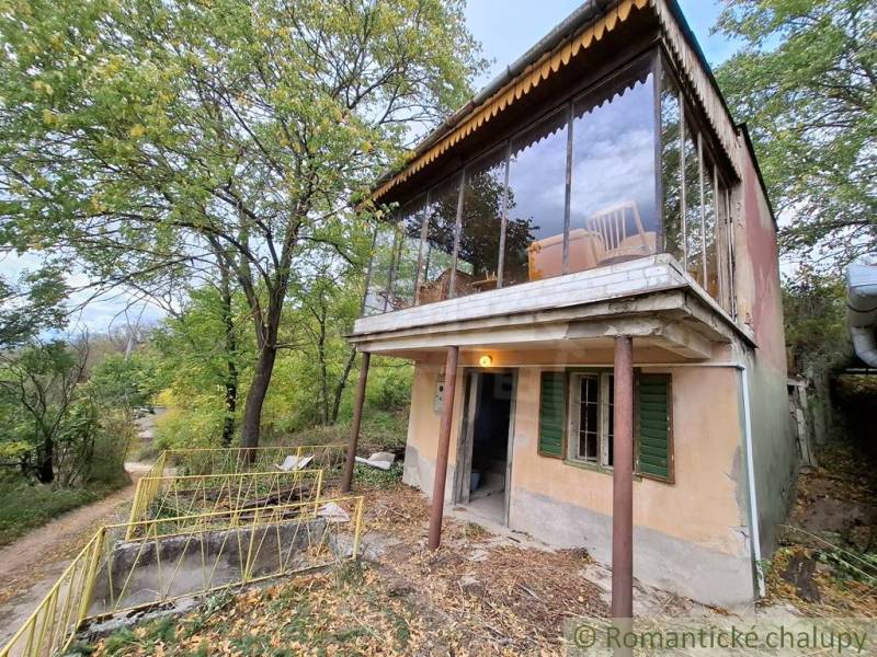 Pôvodná chata s panorámou nad korunami stromov blízko Hrona v rekreačn - Chata v Kameníne obklopená zeleňou, so sklenenou terasou a príjazdovou cestou.