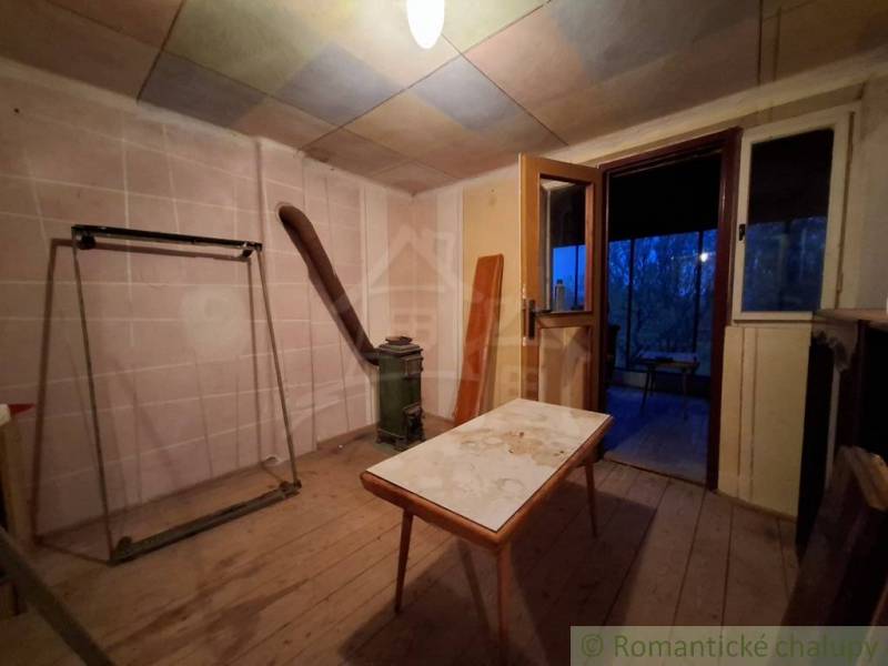 Pôvodná chata s panorámou nad korunami stromov blízko Hrona v rekreačn - Interiér chaty s podlahou s dreveným dekorom a starým nábytkom.