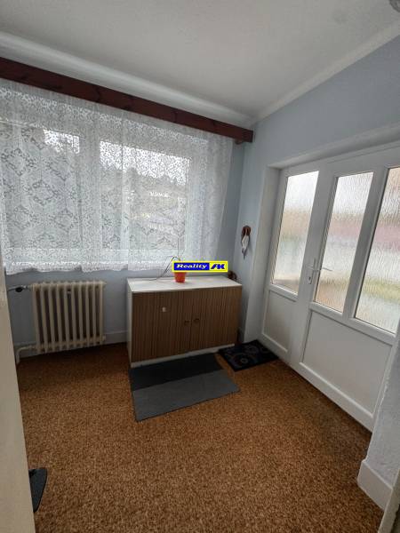 Rodinný dom Martin - Valča - Interiér rodinného domu s kobercom, radiátorom a skrinkou pod oknom.