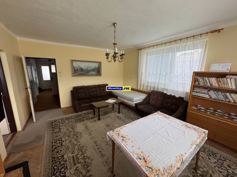 Rodinný dom Martin - Valča - Obývacia izba v rodinnom dome s gaučom, knihovňou a stolom s obrusom.