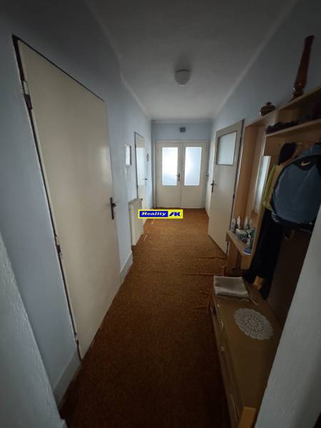 Rodinný dom Martin - Valča - Chodba v rodinnom dome s hnedým kobercom a bielymi dverami.