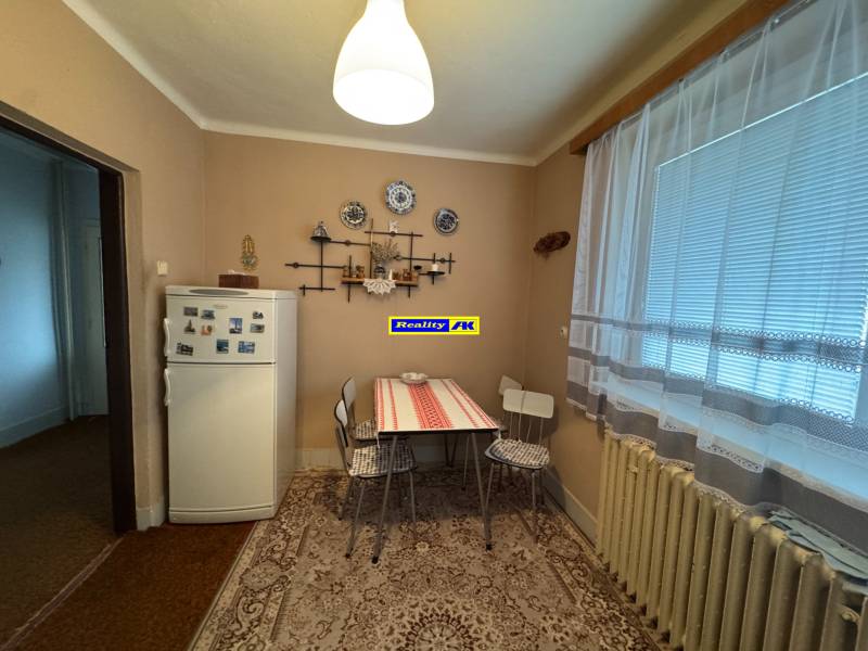 Rodinný dom Martin - Valča - Kuchyňa v rodinnom dome s chladničkou, stolom a dekoračnými predmetmi na stene.