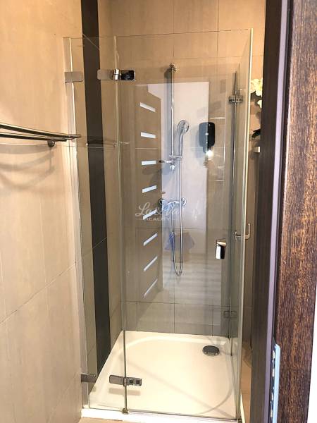 Na predaj apartmán s veľkou terasou Podhájská. - Sprchovací kút so sklenenou zástenou v garsónke s jemnými béžovými obkladačkami.