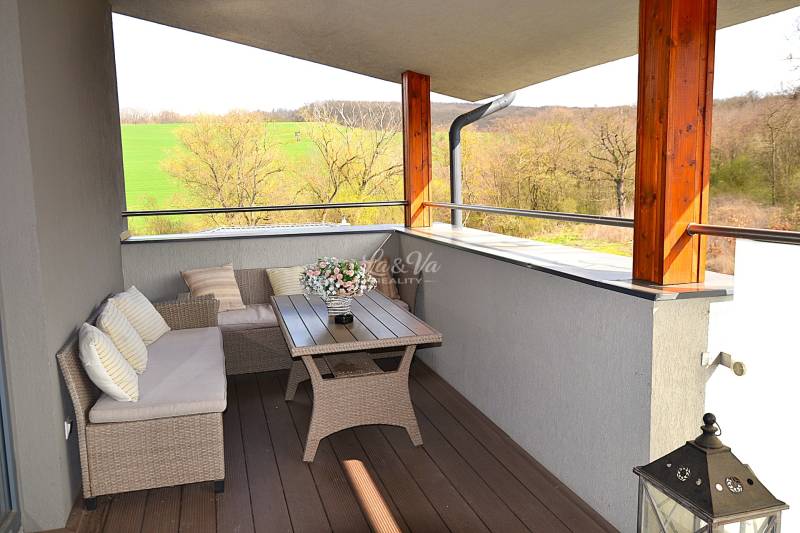 Na predaj apartmán s veľkou terasou Podhájská. - Priestranný balkón s ratanovým nábytkom a podlahou s dreveným dekorom v garsónke.